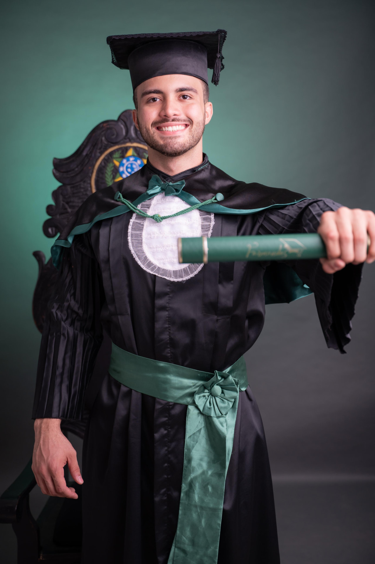 Guilherme Mesquita em sua formatura, de beca e segurando o diploma